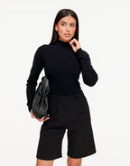 Isolde Black turtleneck sweater with a slim fit and long sleeves, worn with the model's hand raised near her neck.