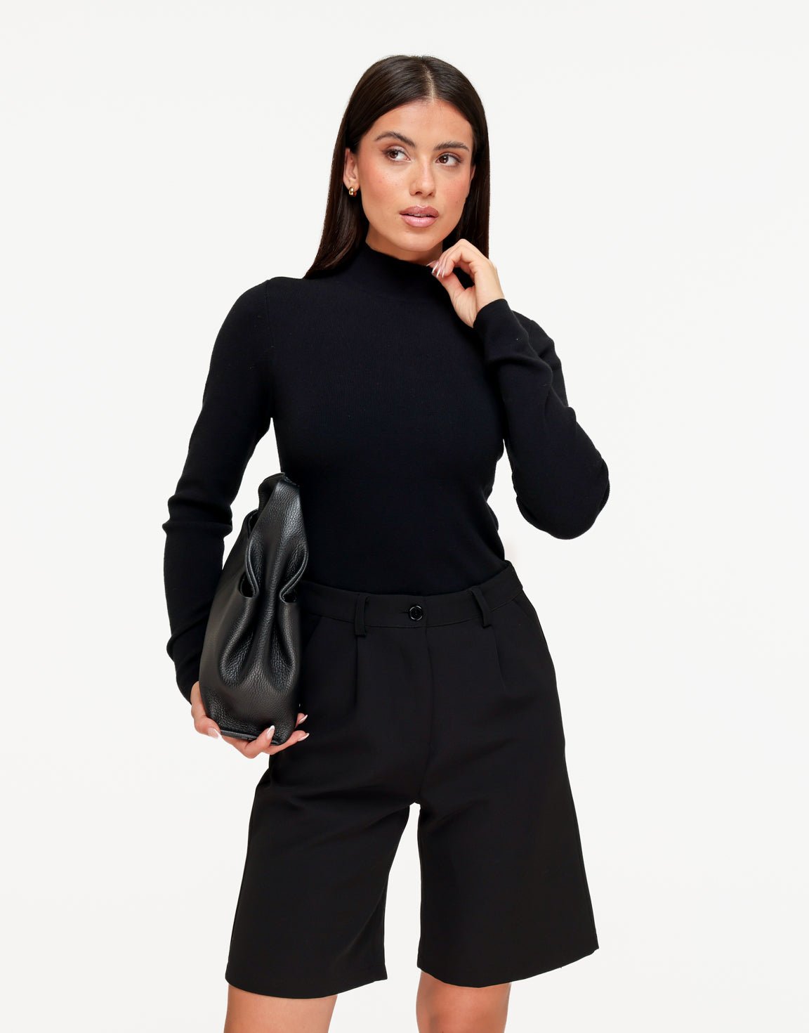 Isolde Black turtleneck sweater with a slim fit and long sleeves, worn with the model's hand raised near her neck.