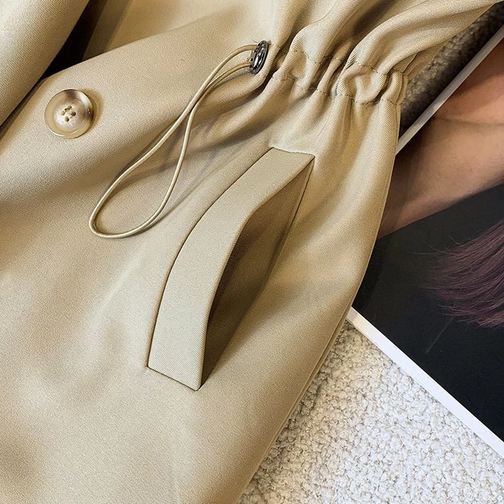 Close-up belt detail of the Jennifer Trench Coat Belted Double-Breasted in khaki, highlighting the matching waist belt and buckle fastening. Designed by Bella Hudson.