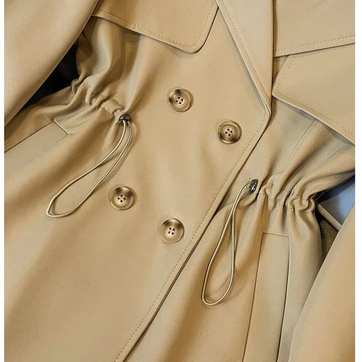 Close-up front detail of the Jennifer Trench Coat Belted Double-Breasted in khaki, featuring the notched lapel collar, double-breasted buttons, waist belt, and structured seam detailing. Designed by Bella Hudson.