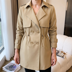 Front model view of the Jennifer Trench Coat Belted Double-Breasted in khaki, featuring wide notched lapels, double-breasted buttons, long sleeves with buckle cuffs, a fitted waist, and flared hem. Designed by Bella Hudson.