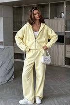 Jolene Yellow zip-up hoodie and wide-leg sweatpants set with front pockets and a white handbag.