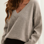 Side view of the Katharina Sweater Knit V-Neck Oversized in beige, showcasing the deep V-neckline, long sleeves, soft knit texture, and loose oversized silhouette. Designed by Bella Hudson.
