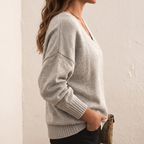 Side view of the Katharina Sweater Knit V-Neck Oversized in beige, showcasing the deep V-neckline, long sleeves, soft knit texture, and relaxed oversized fit. Designed by Bella Hudson.