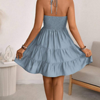 Back view of the Larkin Halter Dress Linen Tiered Bow-Detail in blue, highlighting the halter back, gathered bodice, and softly tiered mini skirt. Designed by Bella Hudson.