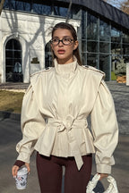 Leona Beige belted peplum jacket shown in a full-body view with a high stand collar, structured shoulders, and cinched waist