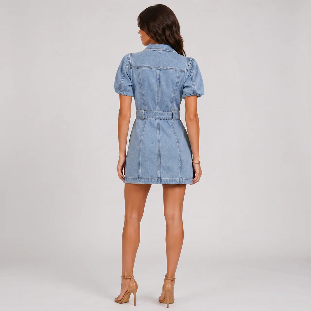 Back view of light wash denim mini dress with puff sleeves and waist belt by BELLA HUDSON