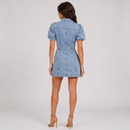 Back view of light wash denim mini dress with puff sleeves and waist belt by BELLA HUDSON