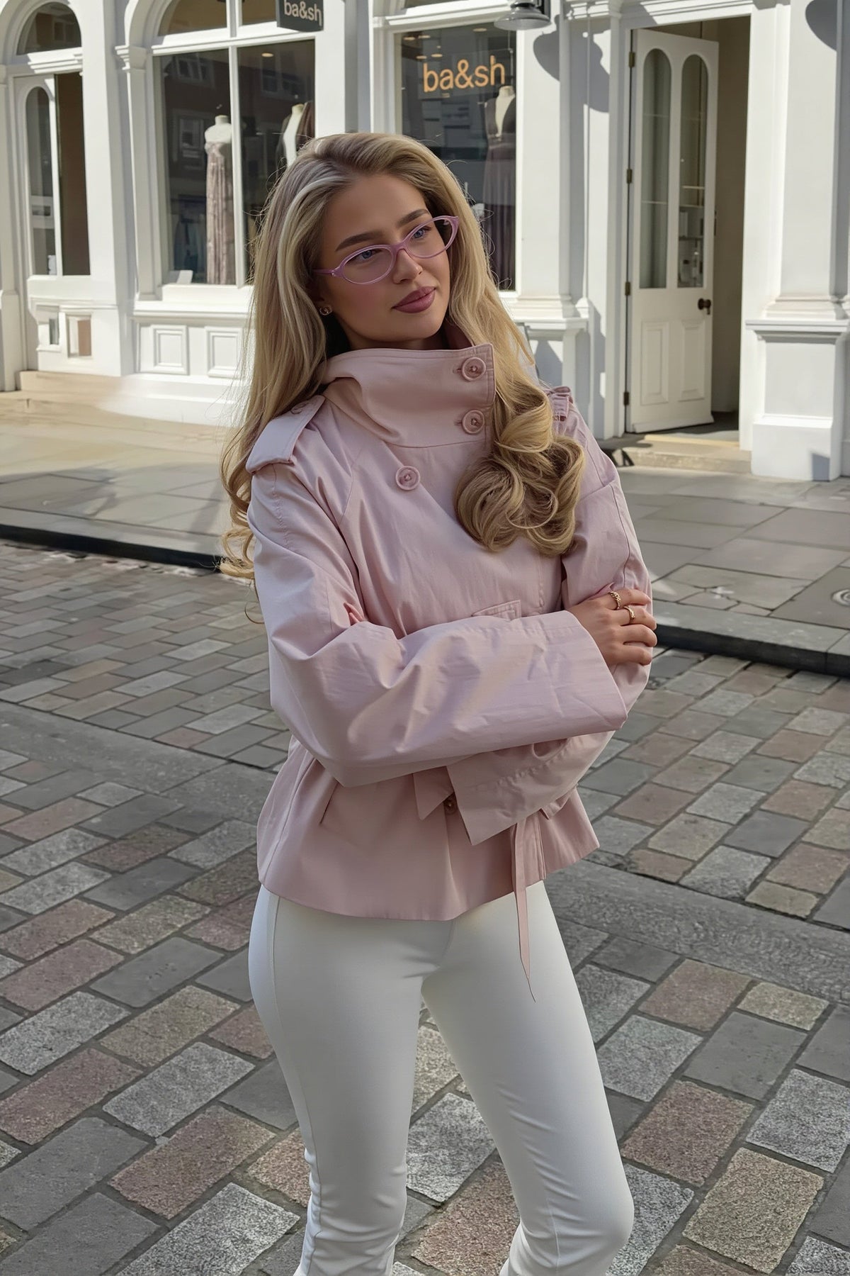 Lila Pink short jacket shown from the side with arms crossed, highlighting the stand collar, epaulettes and flared sleeves.