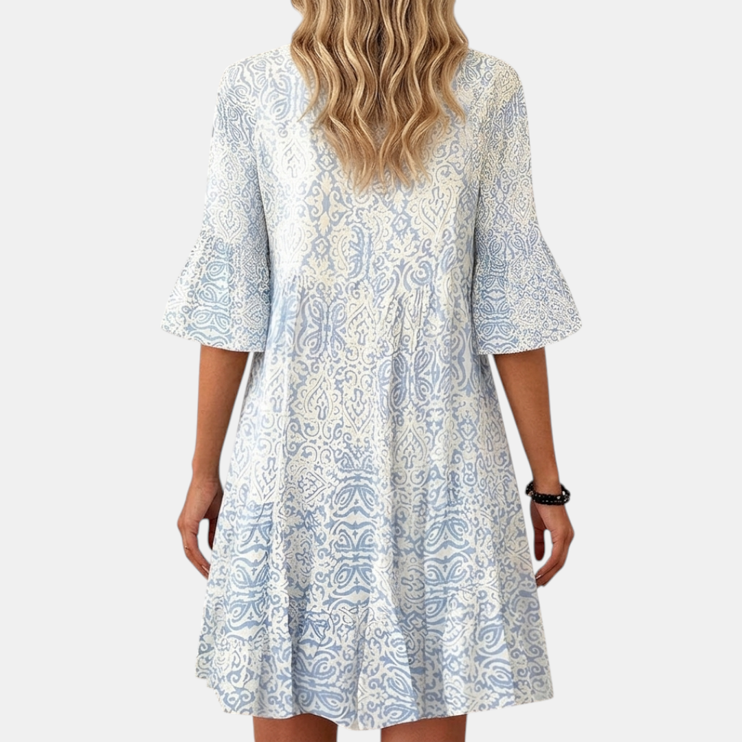 Back view of the Liora Midi Dress Paisley-Print Tiered Tassel-Tie in blue, highlighting the tiered design, three-quarter sleeves, and all-over paisley print. Designed by Bella Hudson.