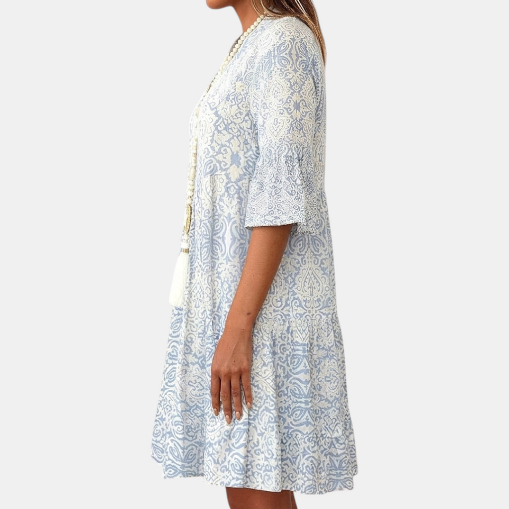Side view of the Liora Midi Dress Paisley-Print Tiered Tassel-Tie in blue, showcasing the relaxed fit, three-quarter sleeves, tiered skirt, and flowing silhouette. Designed by Bella Hudson.