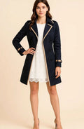 Lydia Black double-breasted trench coat featuring contrast-trimmed notched lapels, front buttons, long sleeves, decorative cuff straps, and a tailored silhouette