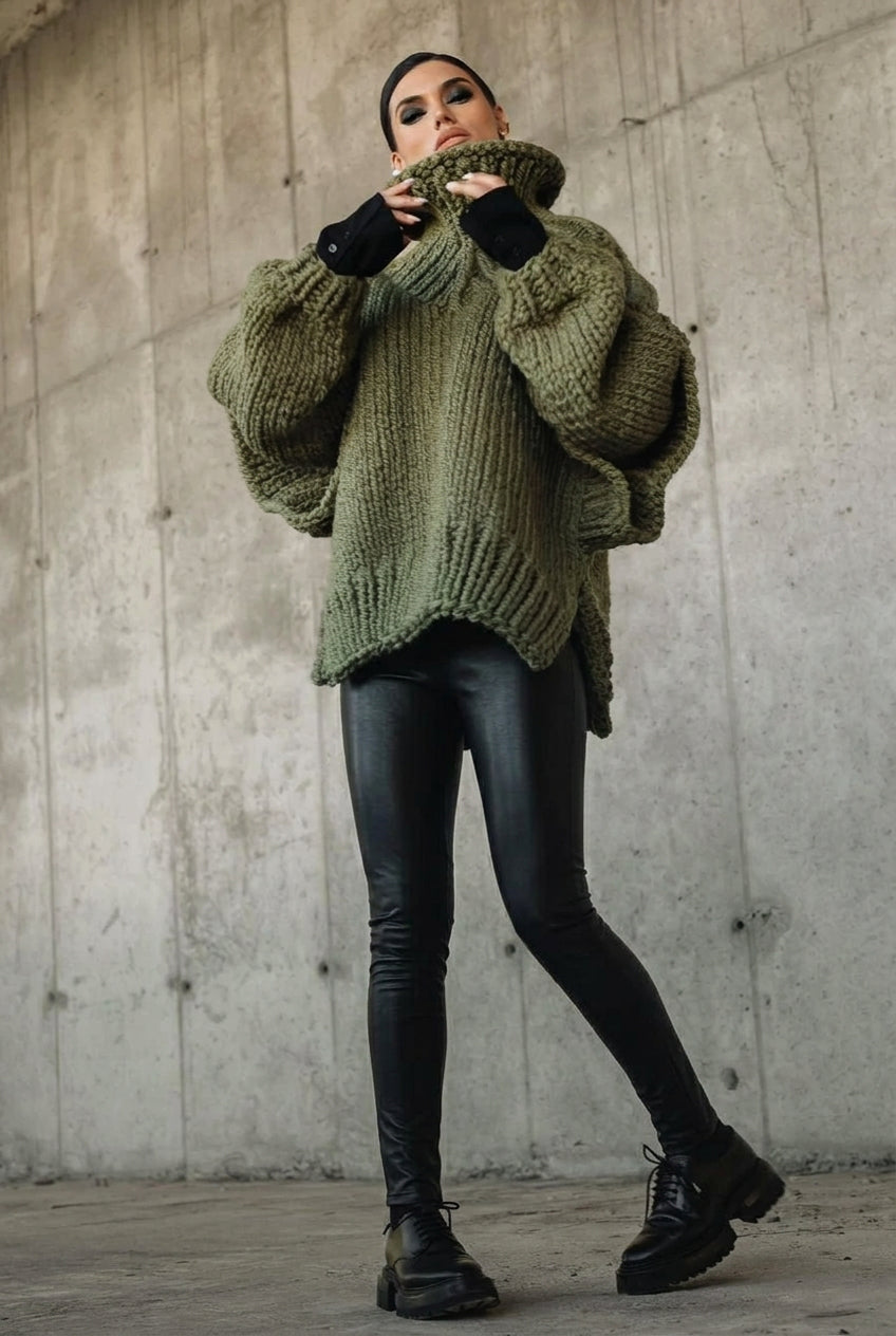 Lydia Green oversized chunky-knit turtleneck sweater with a curved hem, styled with black leggings and lug-sole shoes.