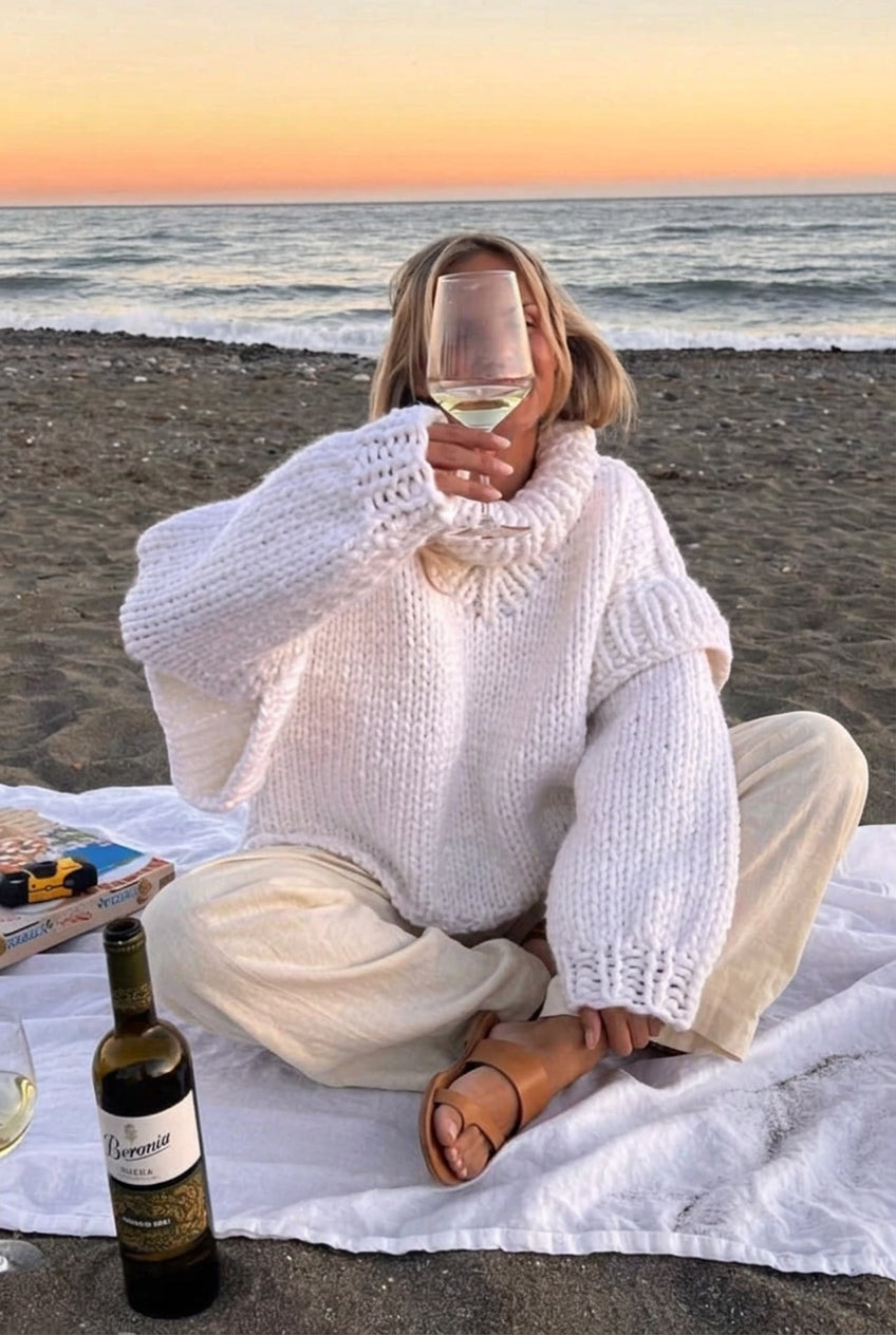 Lydia White chunky-knit turtleneck sweater shown seated with a relaxed silhouette, high collar, and chunky textured finish