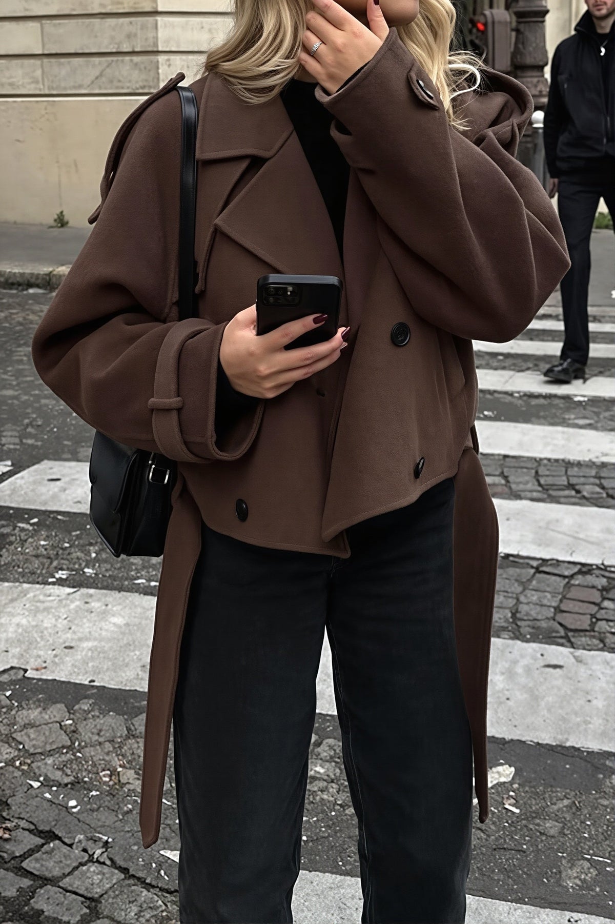 Maren Dark Brown cropped jacket with buckled cuff tabs and dropped shoulders, styled with dark jeans and a black shoulder bag.