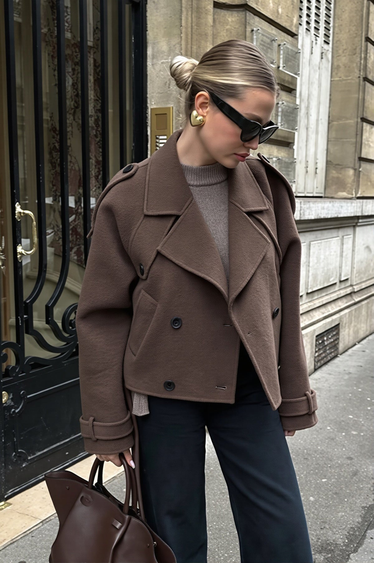 Maren Dark Brown double-breasted cropped jacket styled over a knit sweater with dark trousers and a brown tote on a city street.