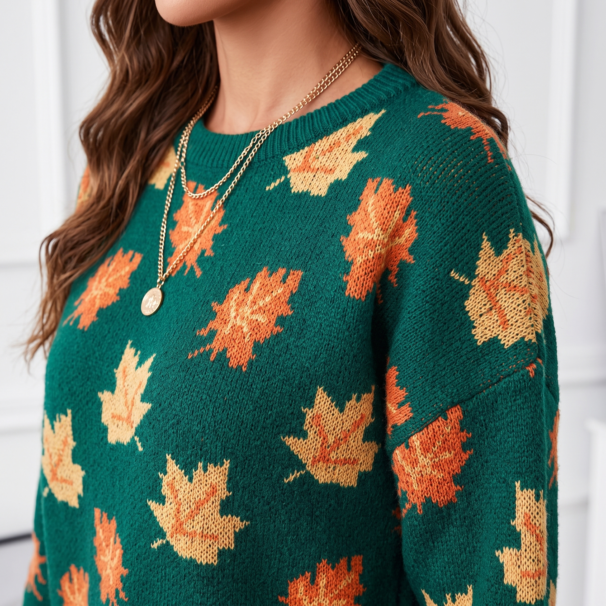 Close-up view of the Marguerite Sweater Leaf-Print Crew-Neck in green, highlighting the round crew neckline, knit texture, and orange and yellow autumn leaf pattern. Designed by Bella Hudson.