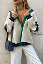 Marielle Green color block cardigan in cream with green and navy trim and striped cuffs, styled with white pants and a navy bag.