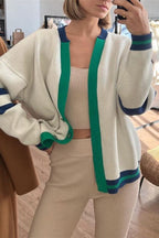 Marielle Green cardigan worn open over a beige ribbed matching set, showing green front trim and navy striped hem.