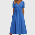Front view of the Marisol Summer Midi Dress Ruched V-Neck in blue, featuring a flattering V-neckline, ruched crossover bodice, short sleeves, flowing midi skirt, and practical side pockets. Designed by Bella Hudson.
