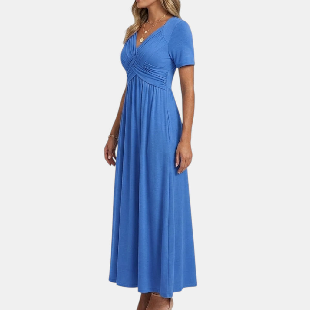 Side view of the Marisol Summer Midi Dress Ruched V-Neck in blue, showcasing the ruched crossover bodice, short sleeves, flowing midi-length silhouette, and side pockets. Designed by Bella Hudson.
