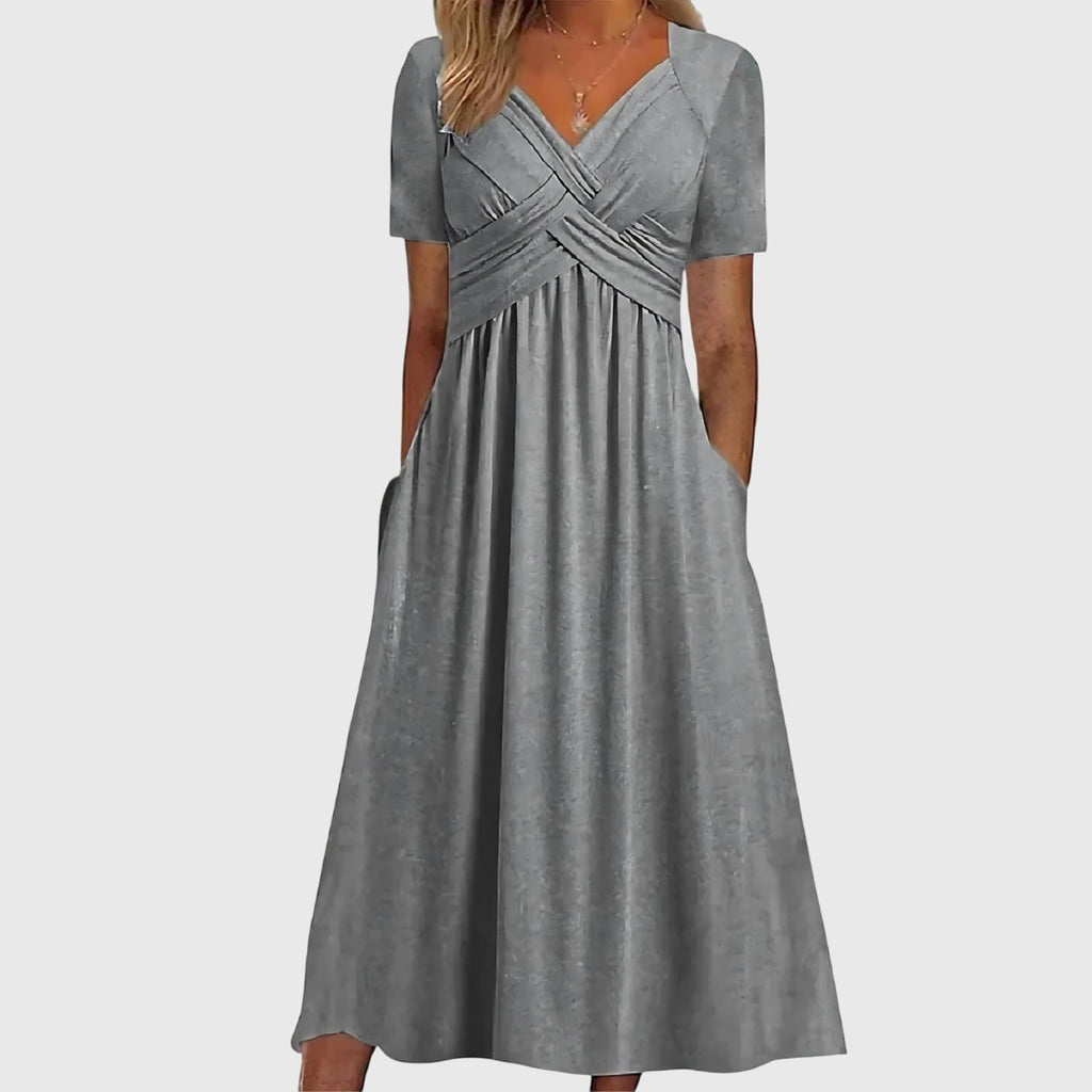Front view of the Marisol Summer Midi Dress Ruched V-Neck in gray, featuring a ruched crossover bodice, V-neckline, short sleeves, flowing midi skirt, and practical side pockets. Designed by Bella Hudson.