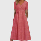 Front view of the Marisol Summer Midi Dress Ruched V-Neck in pink, featuring a flattering V-neckline, ruched crossover bodice, short sleeves, flowing midi-length skirt, and side pockets. Designed by Bella Hudson.