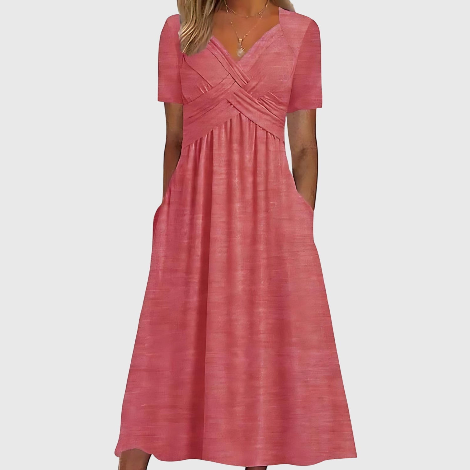Front view of the Marisol Summer Midi Dress Ruched V-Neck in pink, featuring a flattering V-neckline, ruched crossover bodice, short sleeves, flowing midi-length skirt, and side pockets. Designed by Bella Hudson.