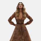 Walking view of the Marlena Maxi Dress Floral-Embroidered Long-Sleeve Boho in dark brown, showcasing the flowing maxi silhouette, embroidered floral details, and effortless bohemian elegance. Designed by Bella Hudson.