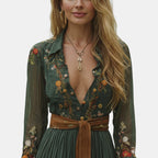 Close-up detail of the Marlena Maxi Dress Floral-Embroidered Long-Sleeve Boho in green, featuring the deep V-neckline, embroidered floral pattern, braided waist belt, and elegant boho styling. Designed by Bella Hudson.