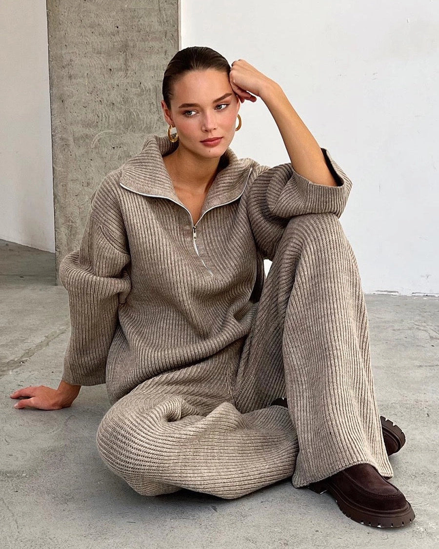Maya Beige ribbed knit lounge set shown seated, featuring a half-zip collared sweater with dropped shoulders and matching wide-leg pants