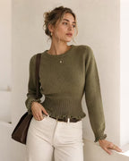 Maya Green ribbed knit sweater with ribbed cuffs and peplum-style hem, worn with white jeans and a brown leather bag.