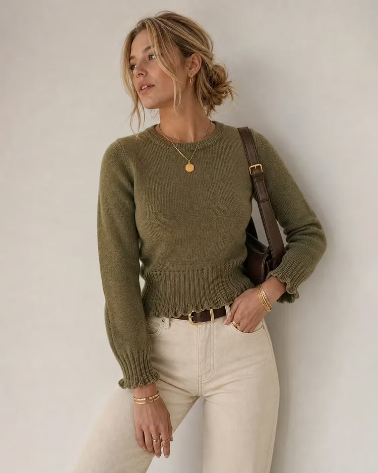 Maya Green ribbed knit sweater showing the ribbed waist and ruffled hem, styled with cream jeans and a brown shoulder bag.