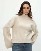 Mila Beige mock-neck sweater worn with jeans, showing the relaxed fit and wide flared sleeves.