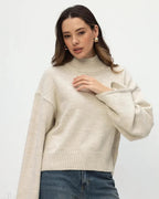 Mila Beige mock-neck sweater with one flared sleeve extended, showing the dropped shoulder and ribbed hem.