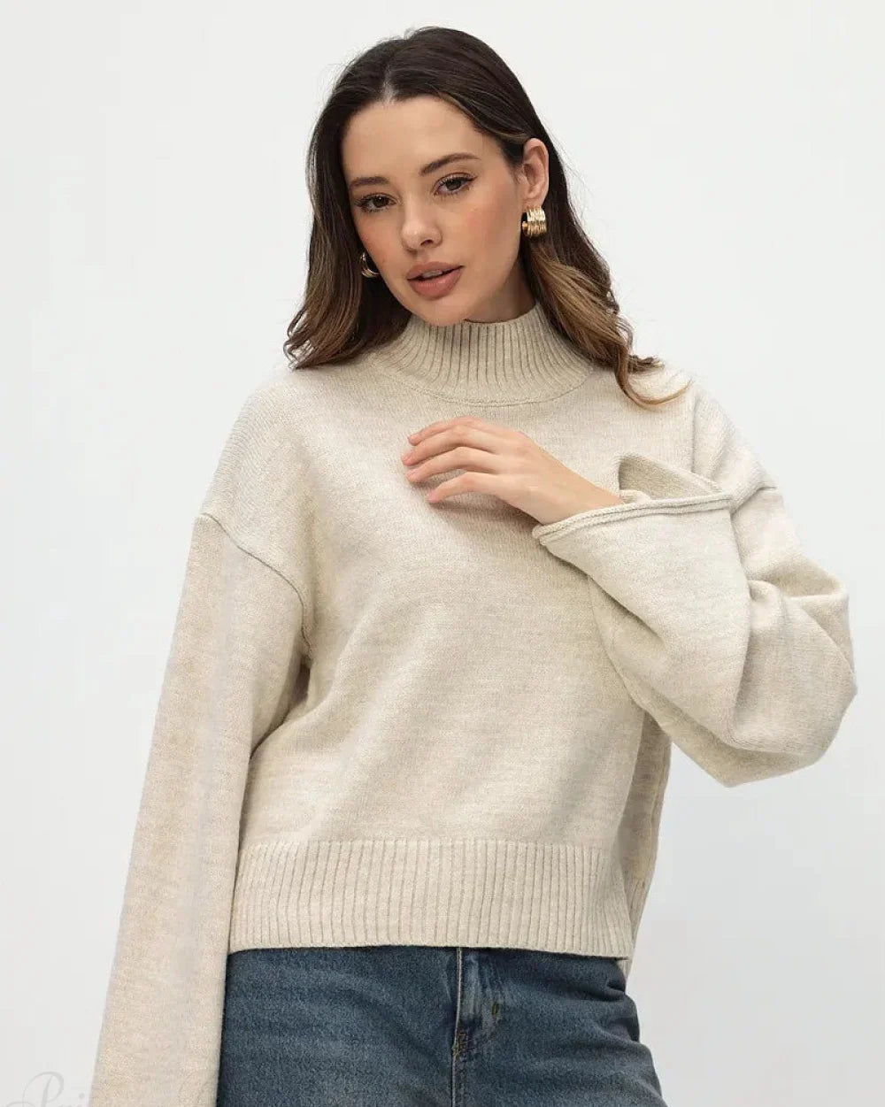 Mila Beige mock-neck sweater with one flared sleeve extended, showing the dropped shoulder and ribbed hem.