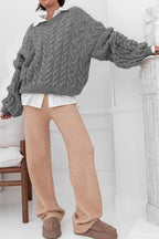 Mila Gray cable-knit sweater styled over a white collared shirt with tan wide-leg pants.