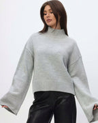 Mila Gray mock-neck sweater with arms out, showing the long flared sleeves.