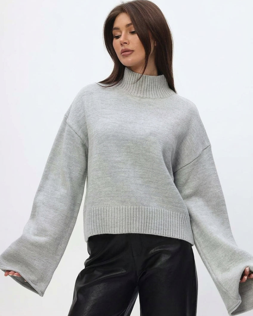 Mila Gray mock-neck sweater with arms out, showing the long flared sleeves.
