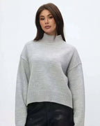 Mila Gray mock-neck sweater worn with black pants, showing the ribbed neckline and straight hem.