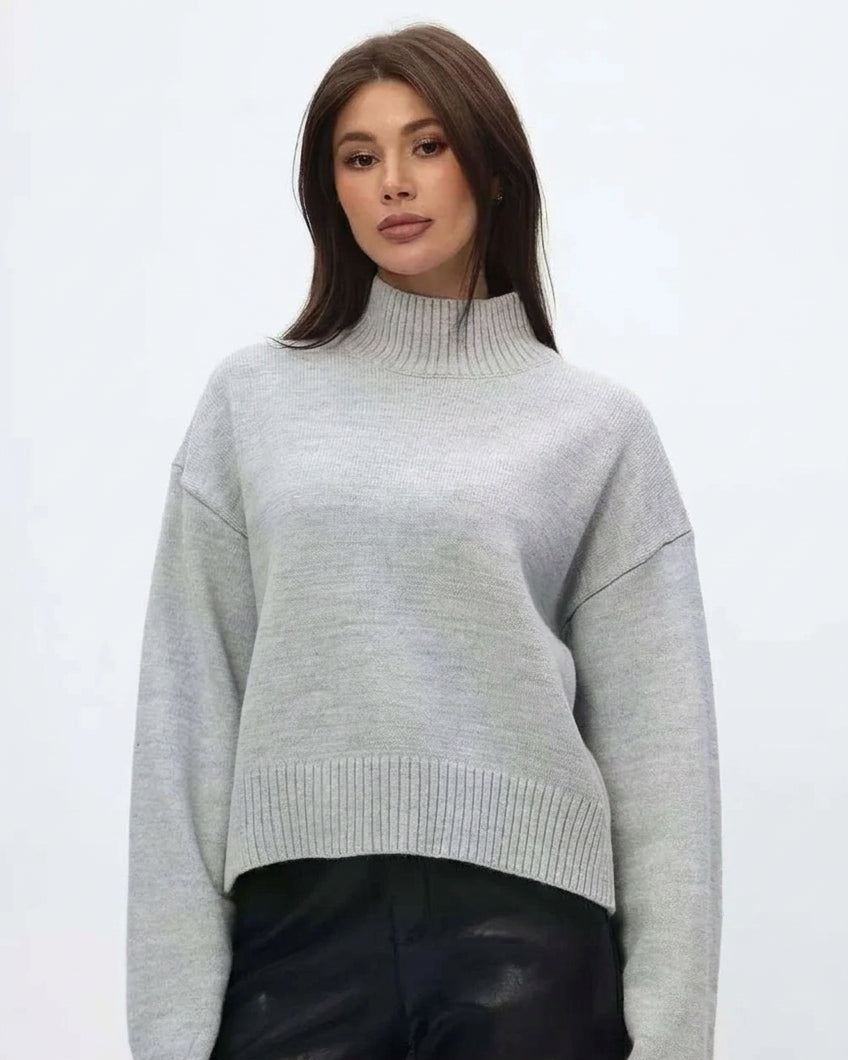 Mila Gray mock-neck sweater worn with black pants, showing the ribbed neckline and straight hem.