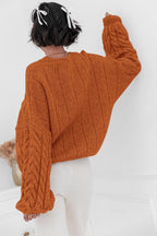 Mila Orange cable-knit sweater shown from the back with ribbed back panels and cable sleeves.