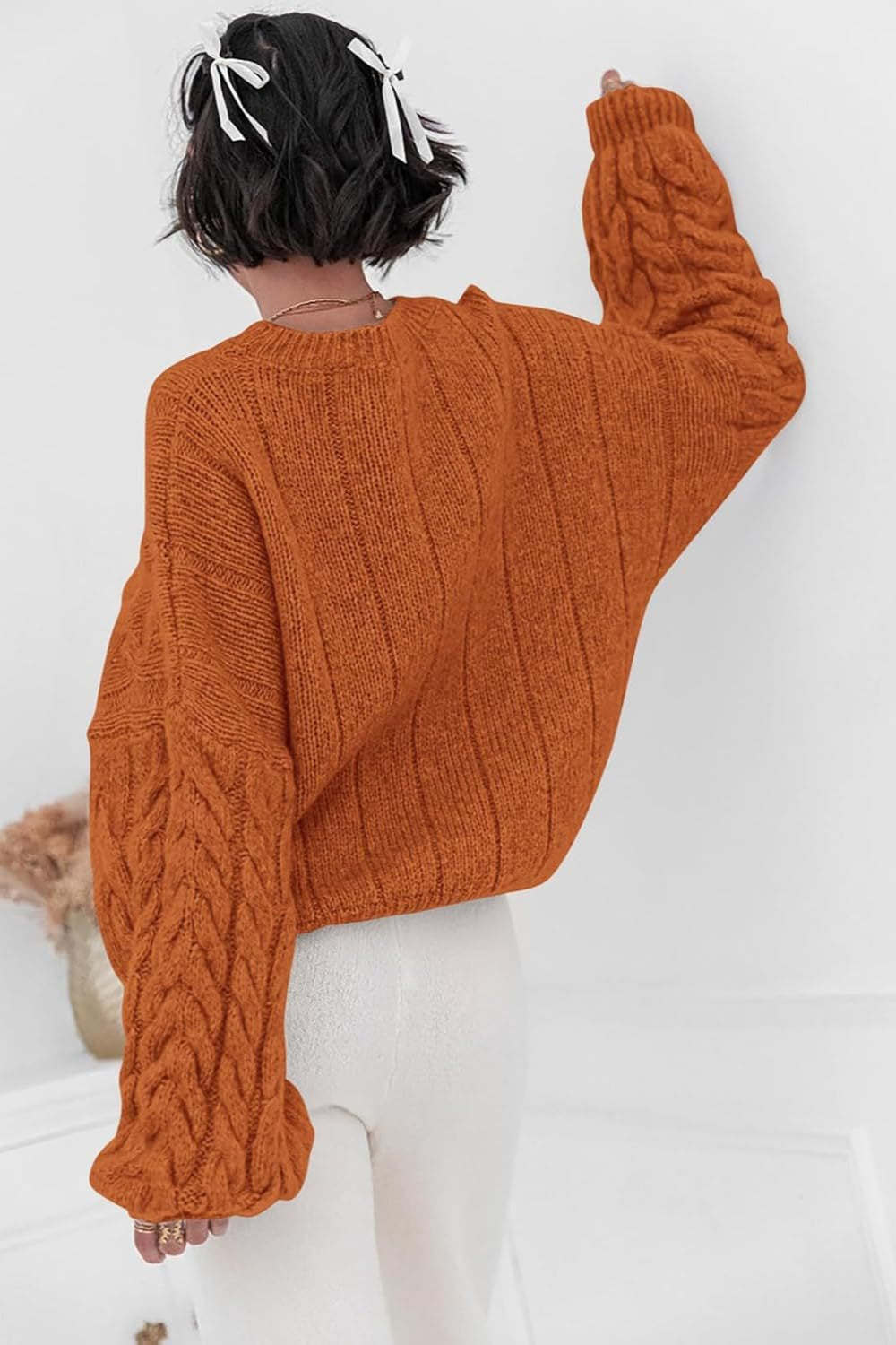 Mila Orange cable-knit sweater shown from the back with ribbed back panels and cable sleeves.