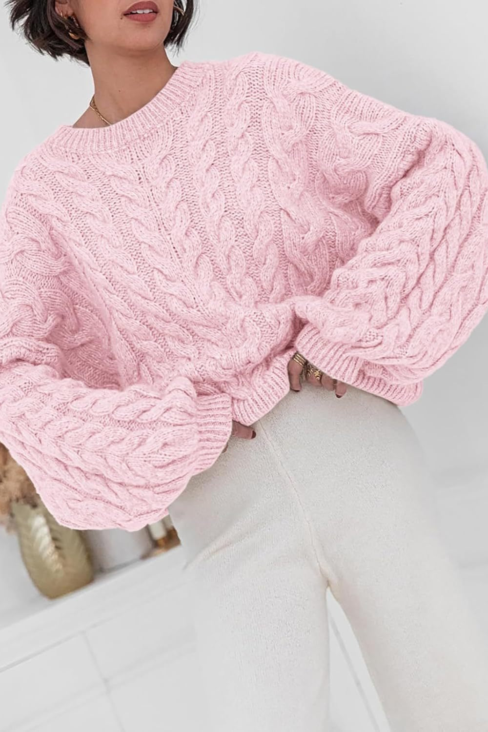 Mila Pink cable-knit crewneck sweater shown from the front with an oversized fit and cable sleeves.
