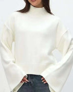Mila White mock-neck sweater worn with jeans, showing the flared sleeves and ribbed hem.