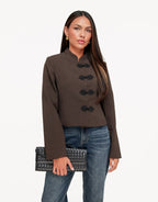 Mirela Dark Khaki cropped jacket with mandarin collar shown from the front while the model holds a woven black clutch.