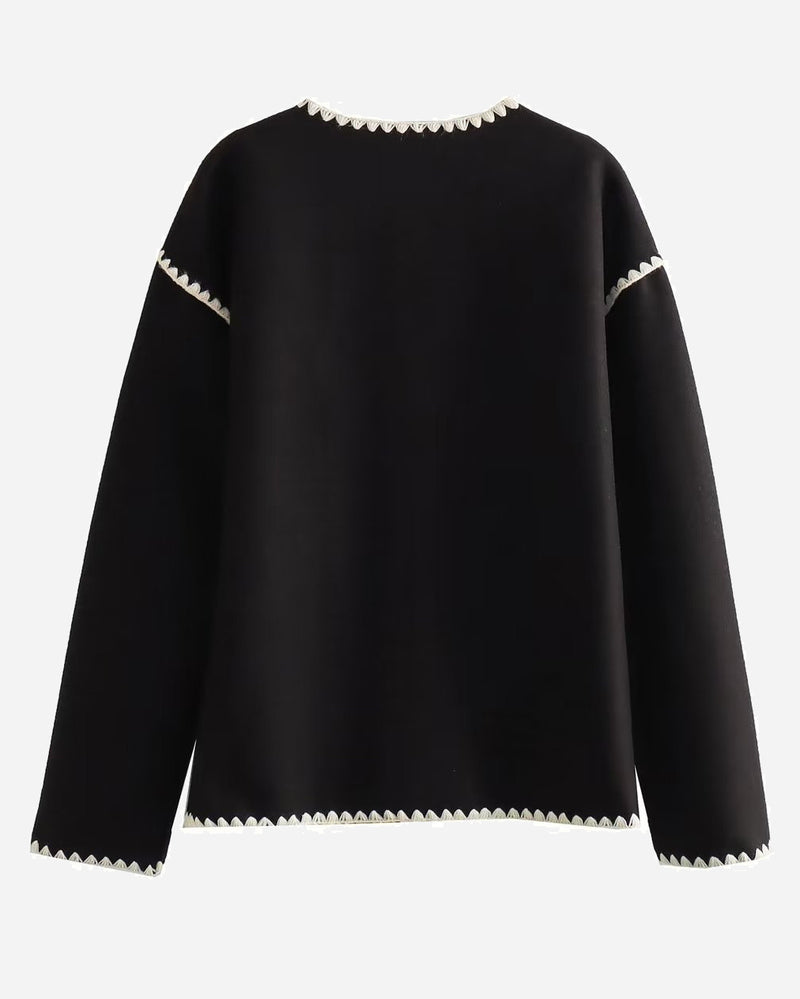 Nadorine Black jacket back view with cream scalloped trim at the neckline, shoulders and hem.