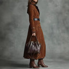Natalie Brown long trench coat shown from the side, featuring a tailored waist, long sleeves, and belted design