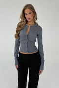 Nina Dark Gray knit cardigan worn buttoned with black pinstripe pants, shown from the front.