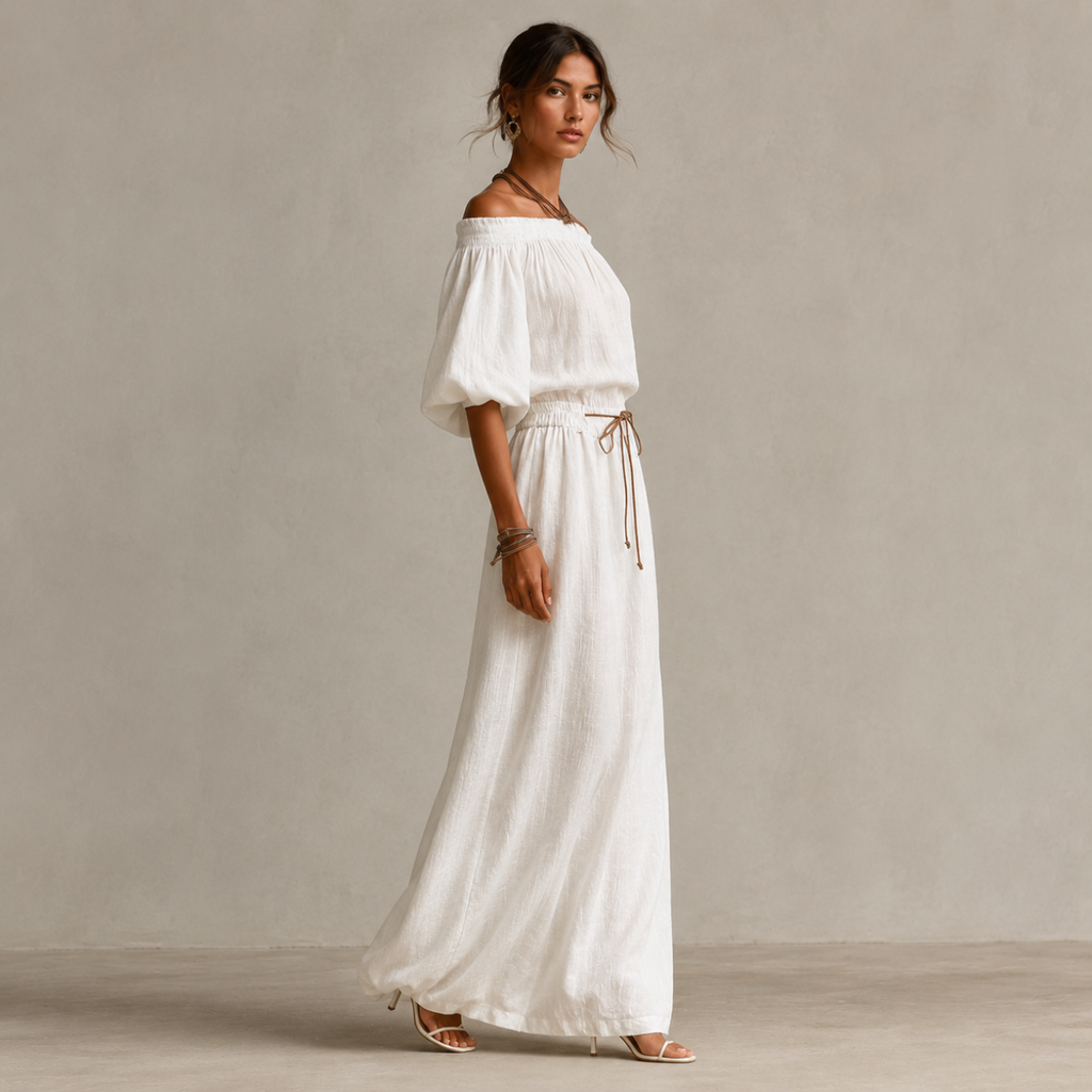 Side view of the Noa Off-Shoulder Lightweight Linen Maxi Dress in white featuring an off-shoulder neckline, lantern sleeves, adjustable waist tie, and flowing maxi-length silhouette. Designed by Bella Hudson.